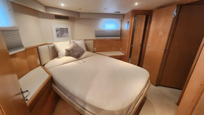 Tropic Jones Yacht Photos Pics Luxurious cabin interior of 1997 Hatteras 52 Cockpit Motor Yacht with cozy bed and wooden furnishings.