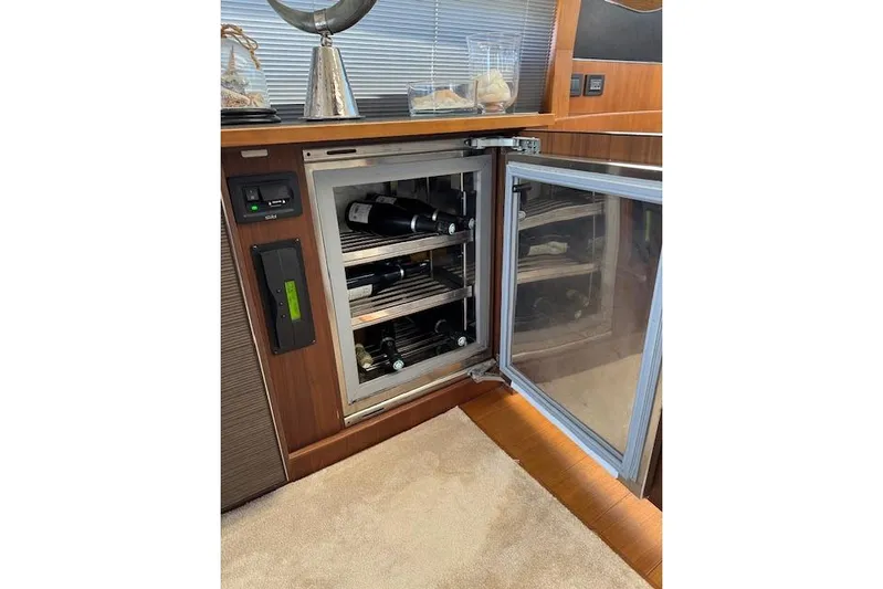  Yacht Photos Pics Open wine cooler on 2014 Princess V 72 yacht, showcasing bottles and elegant interior.