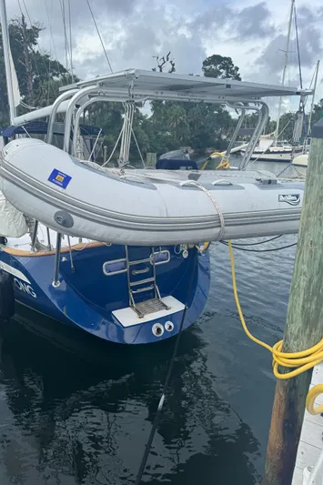 Windsong Yacht Photos Pics 1989 Taswell 49 sailboat with dinghy, docked in a marina, under cloudy skies.