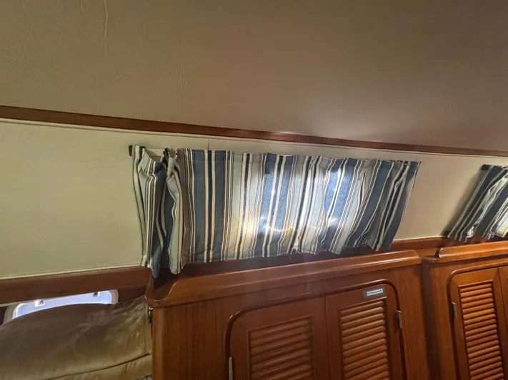 Windsong Yacht Photos Pics Interior of 1989 Taswell 49 yacht with striped curtains and wooden cabinetry.