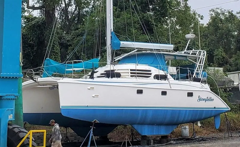 Storyteller Yacht Photos Pics 2007 Manta 42 Mk IV sailing catamaran on land, with blue and white hull, surrounded by trees.