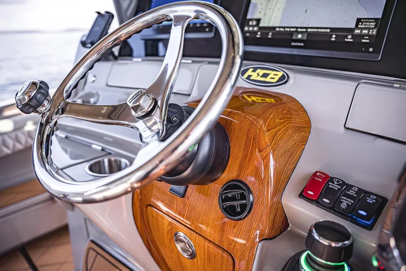 Fifty Shades Of Graydon Yacht Photos Pics Steering wheel and controls of 2023 HCB 42 Lujo boat, featuring wood accents and navigation display.
