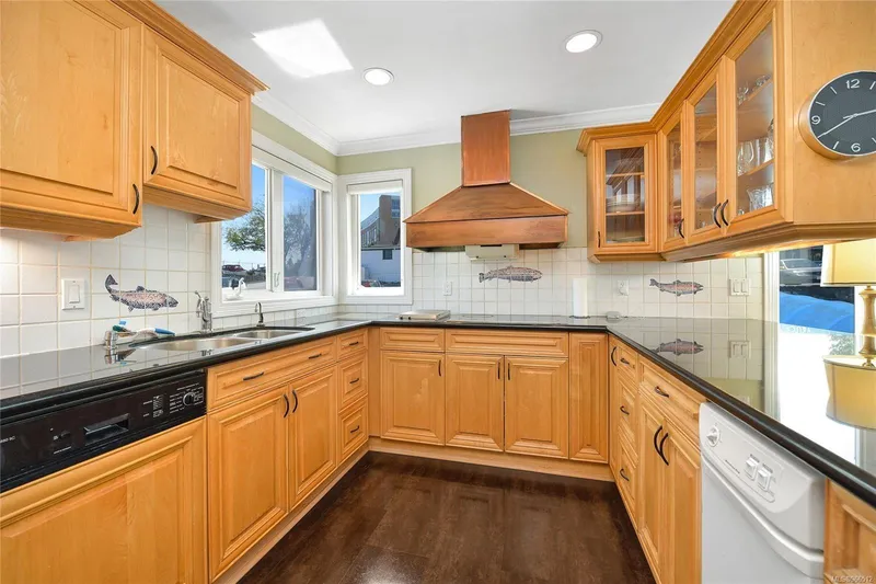  Yacht Photos Pics Wooden kitchen in a 2005 custom float home with black countertops and fish-themed tiles.
