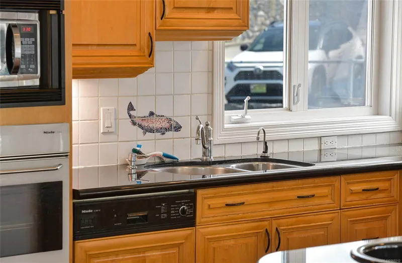  Yacht Photos Pics Kitchen with wooden cabinets, black countertop, fish tile design, and stainless steel sink.