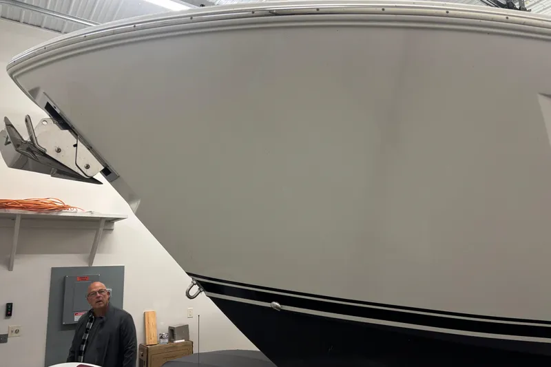  Yacht Photos Pics 2020 Pursuit DC 365 Dual Console boat in indoor storage, with visible anchor and man nearby.