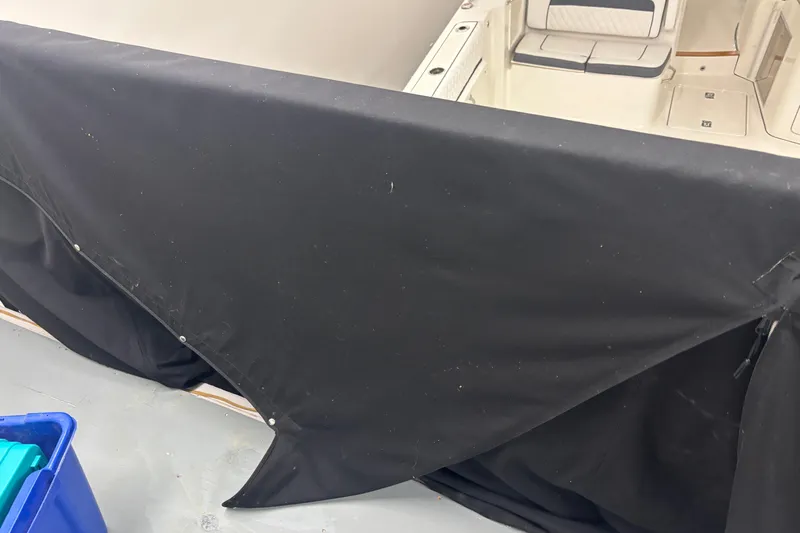  Yacht Photos Pics 2020 Pursuit DC 365 Dual Console boat partially covered with black tarp in storage.