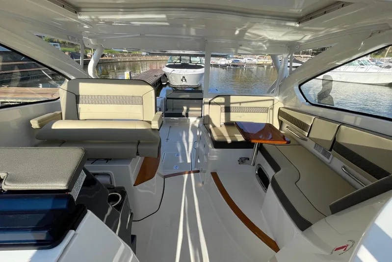  Yacht Photos Pics 2020 Pursuit DC 365 Dual Console boat interior with seating and table, docked at marina.