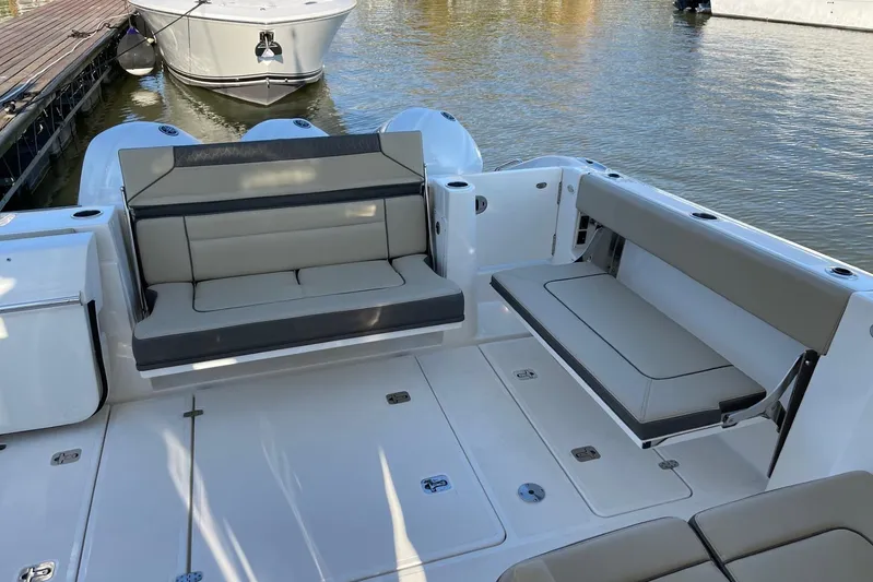  Yacht Photos Pics 2020 Pursuit DC 365 Dual Console boat interior with cushioned seating, docked on calm water.
