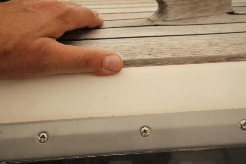 Le Reve Yacht Photos Pics Hand touching teak deck of 1983 Nautor Swan 46mkI sailboat, showcasing craftsmanship.