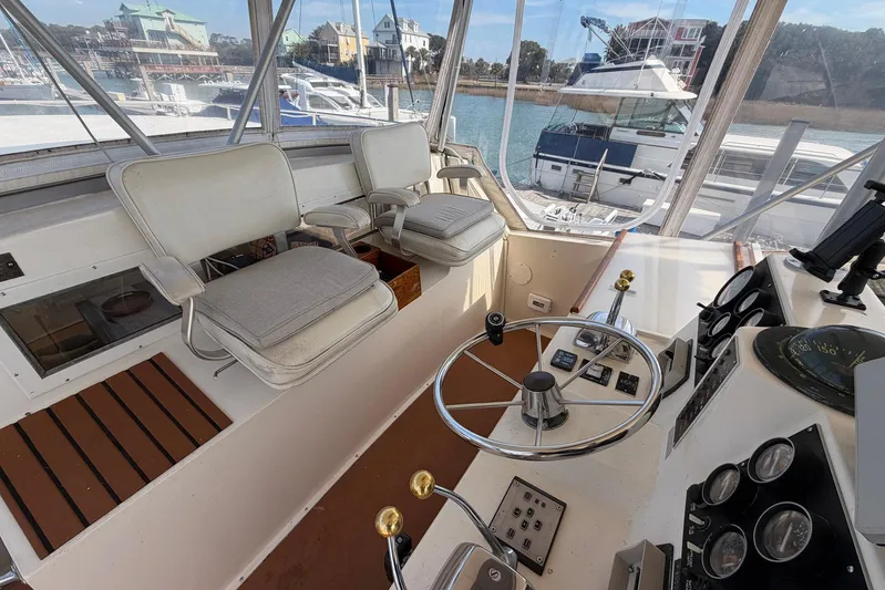 Frayed Knot Yacht Photos Pics 1987 Viking 44 Motor Yacht helm with steering wheel, controls, and seating, docked at marina.