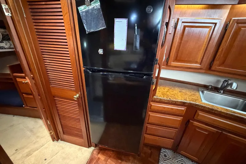 Frayed Knot Yacht Photos Pics 1987 Viking 44 Motor Yacht kitchen with black fridge, wooden cabinets, and sink.