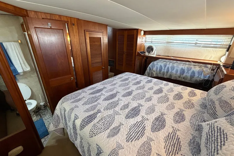 Frayed Knot Yacht Photos Pics 1987 Viking 44 Motor Yacht bedroom with patterned bedding and wooden cabinetry.
