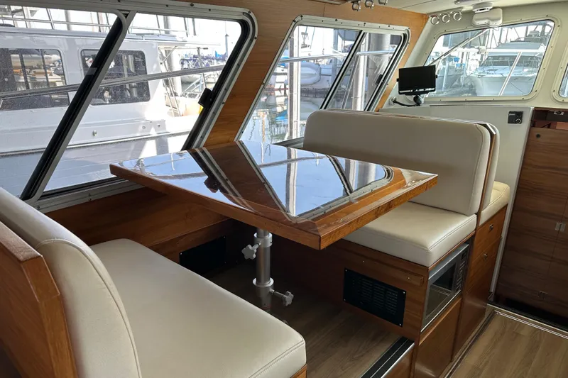 Reel Salty Yacht Photos Pics 2020 Coastal Craft 33 ProFish interior with dining area, wooden table, and cushioned seating.