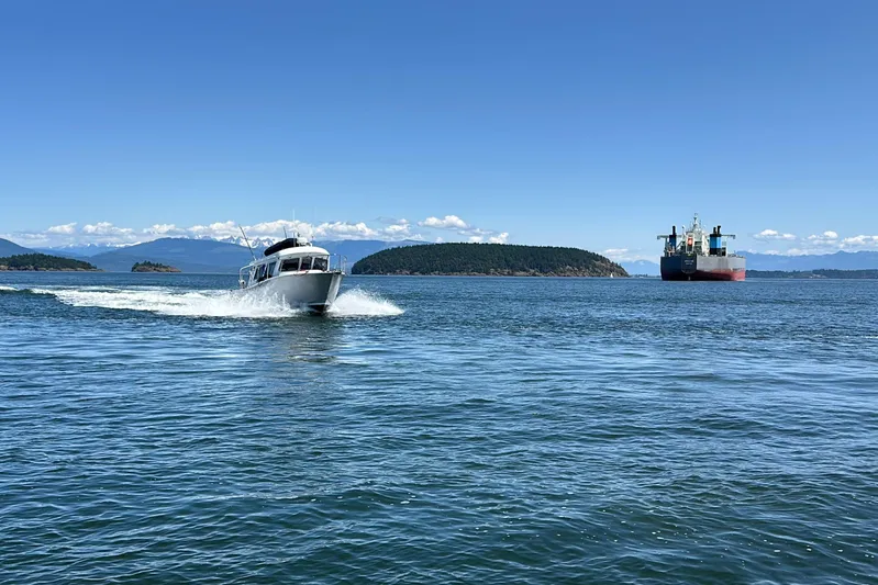 Reel Salty Yacht Photos Pics 2020 Coastal Craft 33 ProFish cruising on open water with distant cargo ship.