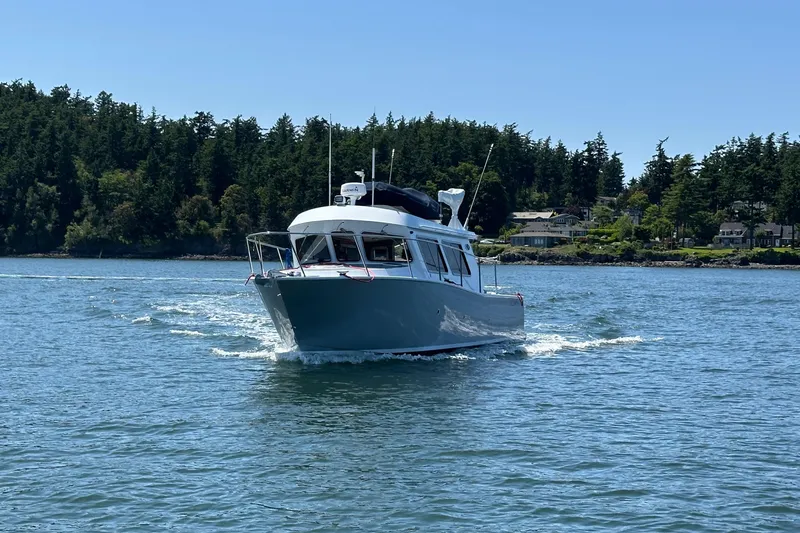 Reel Salty Yacht Photos Pics 2020 Coastal Craft 33 ProFish boat cruising on a sunny day near a forested shoreline.