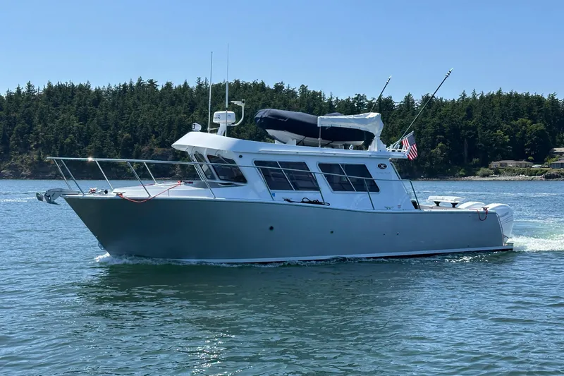 Reel Salty Yacht Photos Pics 2020 Coastal Craft 33 ProFish boat cruising on a serene lake with forested shoreline.