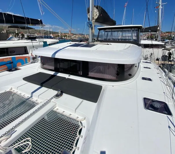  Yacht Photos Pics 2024 Lagoon 42 catamaran docked in a marina under clear blue skies.