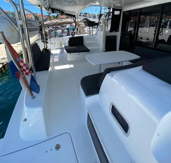  Yacht Photos Pics 2024 Lagoon 42 yacht deck with seating, table, and Croatian flag in marina.