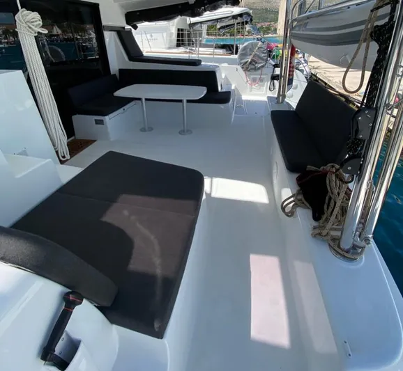  Yacht Photos Pics 2024 Lagoon 42 catamaran deck with seating and table, docked by the water.