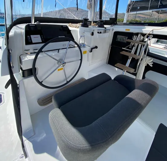 Yacht Photos Pics 2024 Lagoon 42 yacht helm station with steering wheel and comfortable seating.