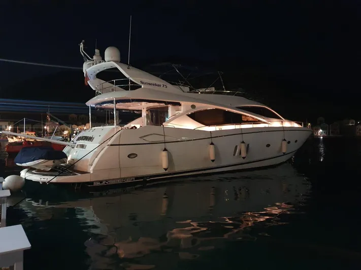 Tais Octavia Yacht Photos Pics Luxurious 2005 Sunseeker 75 yacht docked at night, illuminated and reflecting on water.