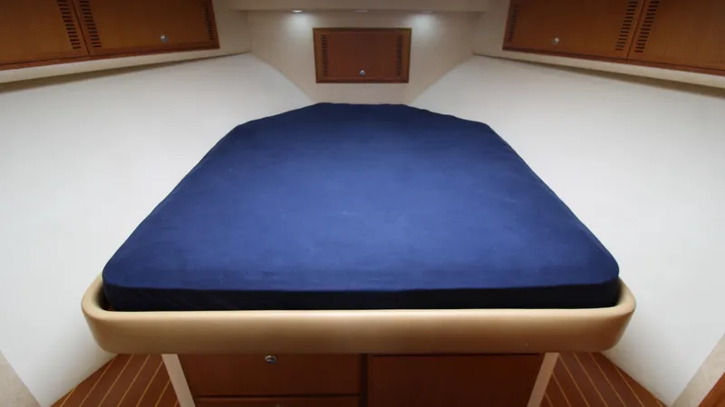 Feeva Yacht Photos Pics 2007 Cabo 40 Hardtop Express cabin with blue bed, wooden accents, and overhead lighting.