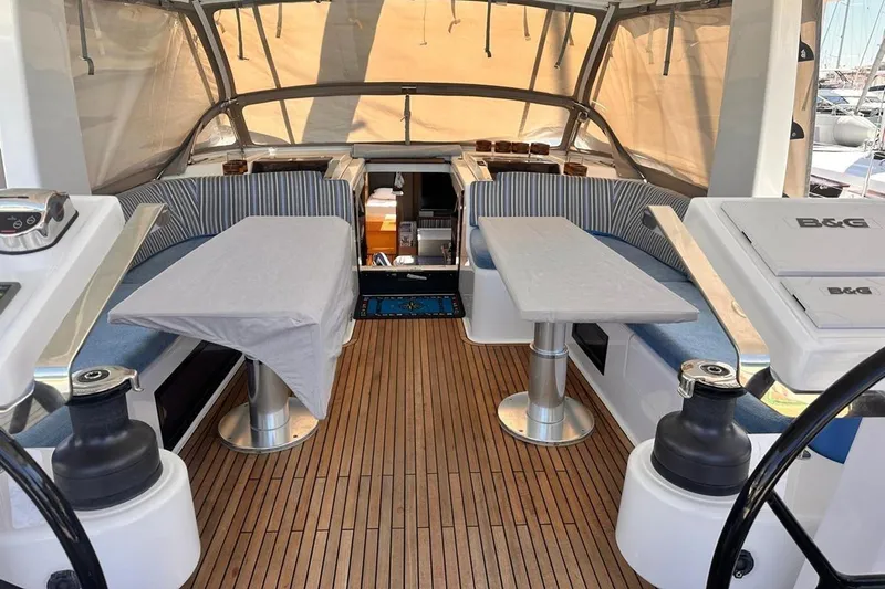  Yacht Photos Pics 2018 Hanse 548 yacht cockpit with striped seating, dual tables, and teak flooring.