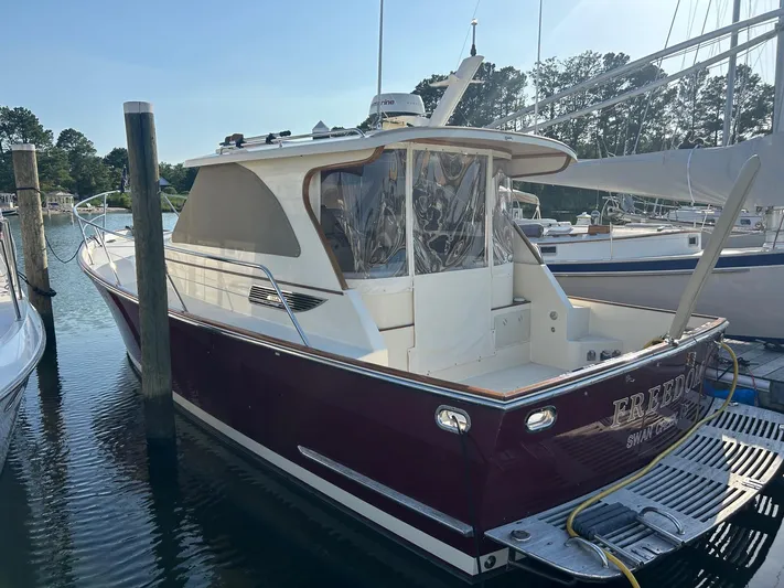 Freedom Yacht Photos Pics 2008 Legacy 32 boat docked in marina, featuring maroon hull and enclosed cabin.