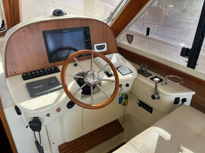 Freedom Yacht Photos Pics Helm of 2008 Legacy 32 boat with wooden steering wheel and Raymarine navigation system.
