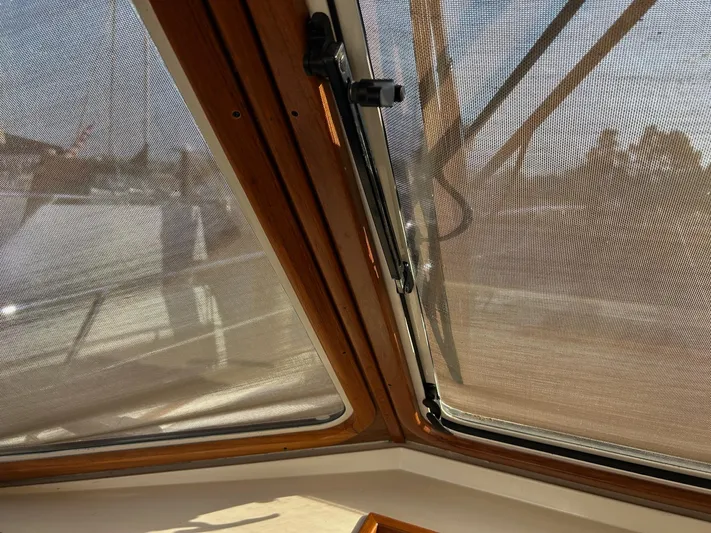 Freedom Yacht Photos Pics Interior view through mesh window of 2008 Legacy 32 boat, showcasing wooden frame details.