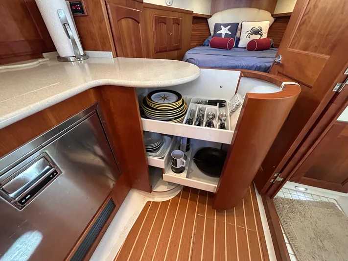 Freedom Yacht Photos Pics Interior of 2008 Legacy 32 yacht with open kitchen cabinet displaying dishes and utensils.