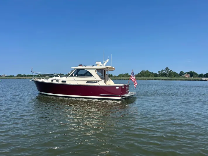 Freedom Yacht Photos Pics 2008 Legacy 32 boat on calm water with American flag, clear blue sky.
