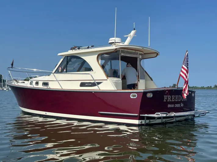 Freedom Yacht Photos Pics 2008 Legacy 32 boat named "Freedom" on water, American flag, clear sky.