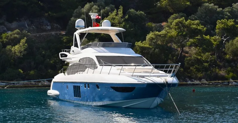  Yacht Photos Pics Luxurious 2010 Azimut 64 yacht anchored in serene waters, surrounded by lush greenery.