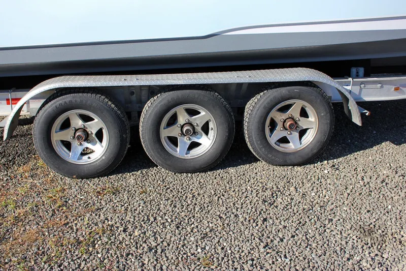  Yacht Photos Pics Triple-axle trailer for 2018 Sea Hunt Gamefish 30 on gravel surface.