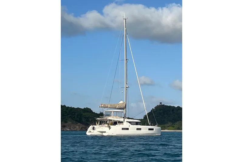  Yacht Photos Pics 2022 Lagoon 46 catamaran sailing on blue waters with lush green hills in the background.