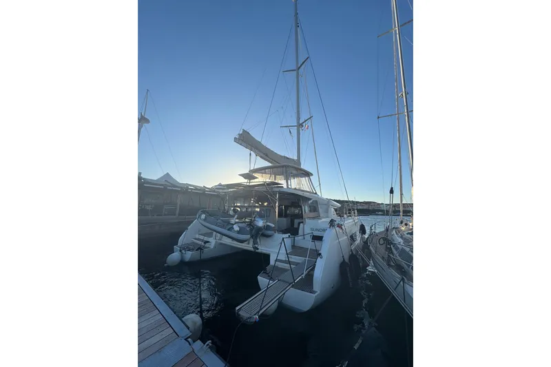  Yacht Photos Pics 2022 Lagoon 46 catamaran docked at marina during sunset.