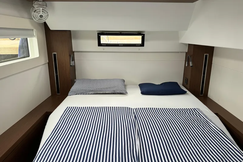  Yacht Photos Pics Interior cabin of 2022 Lagoon 46 yacht with striped bedding and modern design.