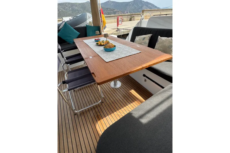  Yacht Photos Pics Luxurious 2022 Lagoon 46 yacht deck with dining table and scenic mountain view.