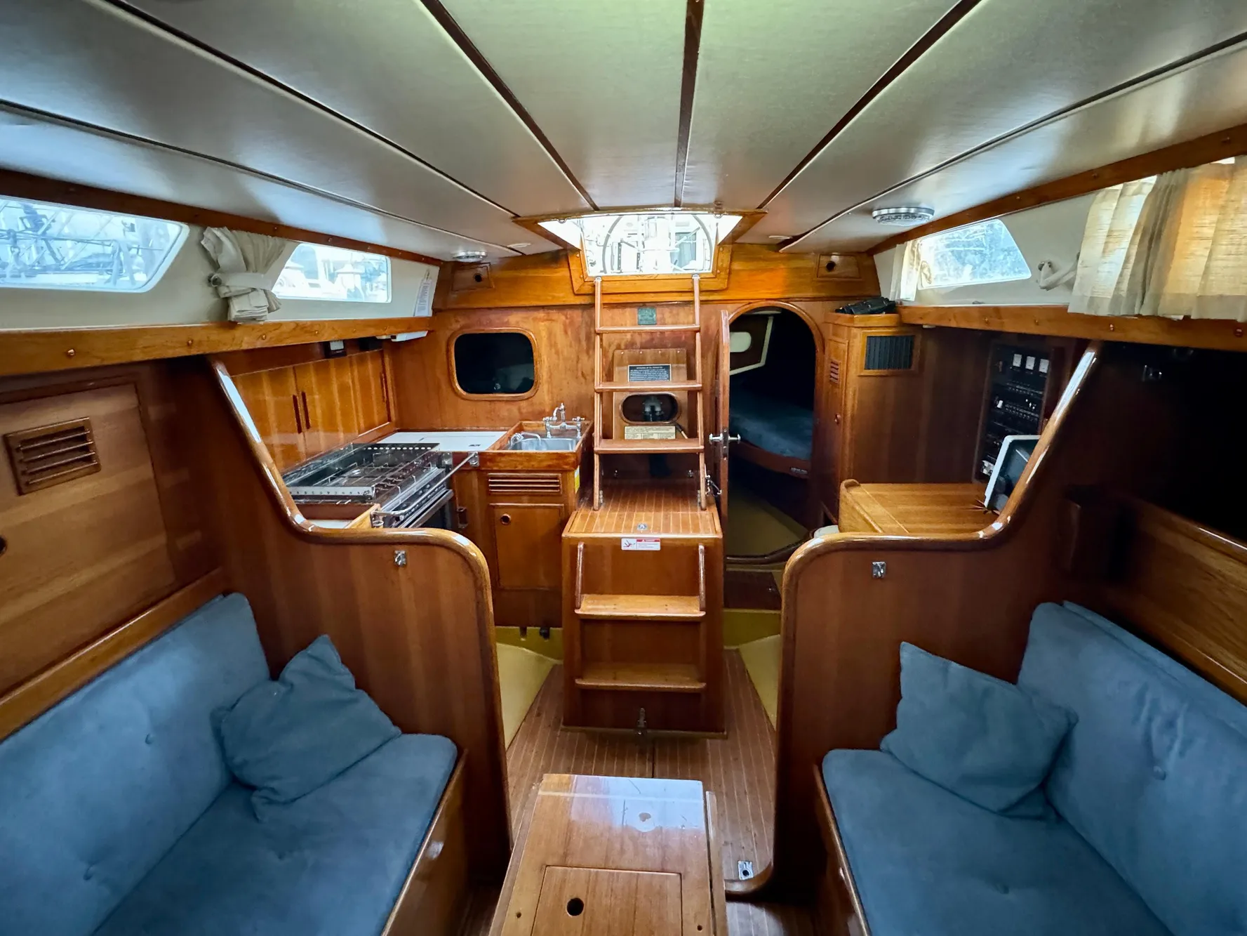Interior of 1974 Nautor Swan 38 sailboat with wooden finish and cozy seating.