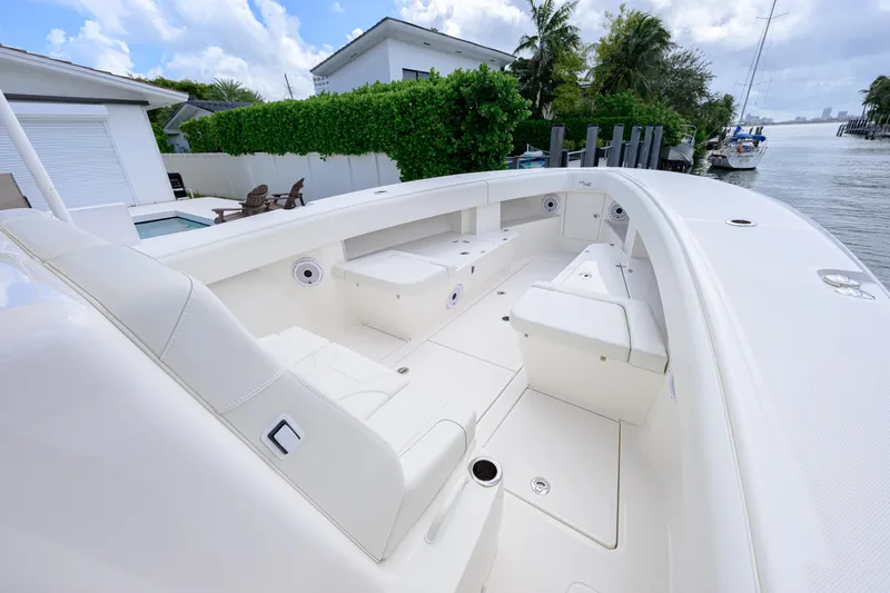 Seavee Yacht Photos Pics 2023 SeaVee 370z boat interior with white seating, docked by a waterfront home.