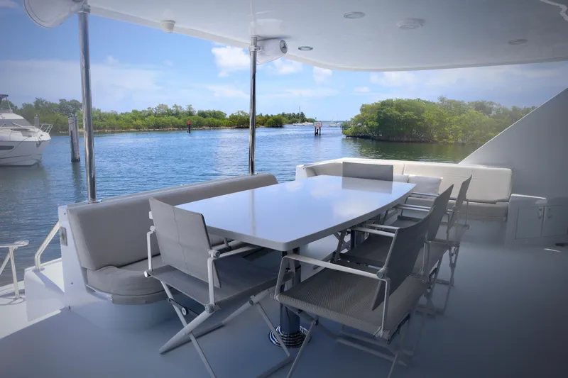 Soul Yacht Photos Pics Outdoor dining area on 2002 Hatteras 92 Cockpit Motor Yacht, overlooking serene water and lush greenery.