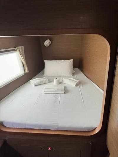 Oscar III Yacht Photos Pics Cozy cabin bed in 2018 Lagoon 380 catamaran with window, pillows, and towels.