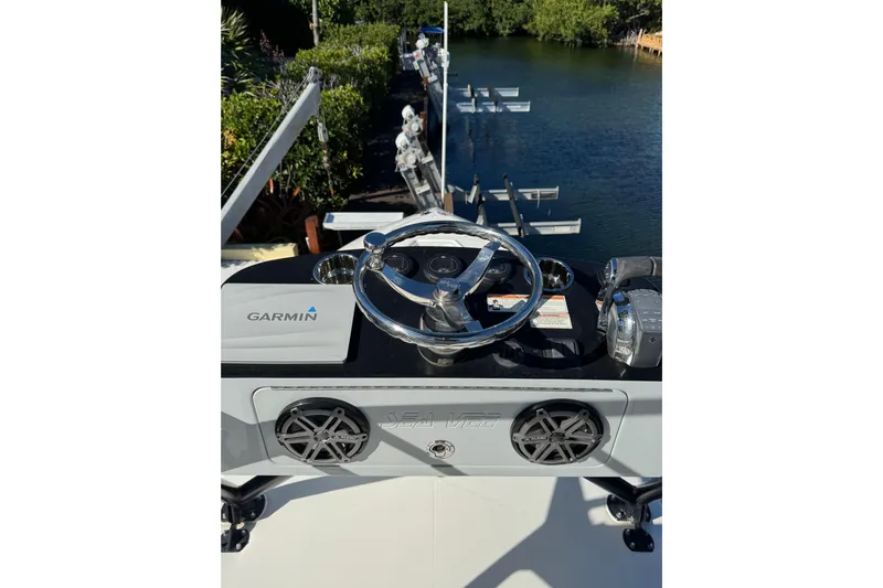  Yacht Photos Pics 2019 SeaVee 370Z boat helm with Garmin system, docked near lush greenery.