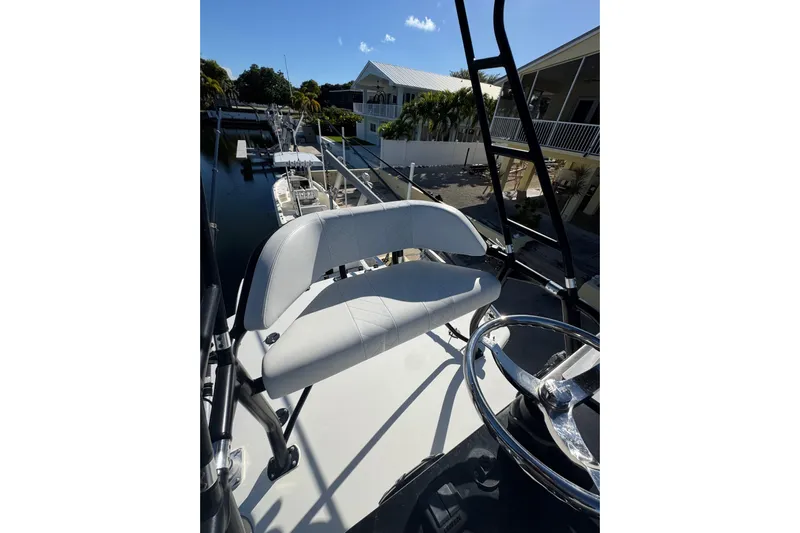  Yacht Photos Pics 2019 SeaVee 370Z boat helm with white seating and steering wheel, docked near waterfront homes.