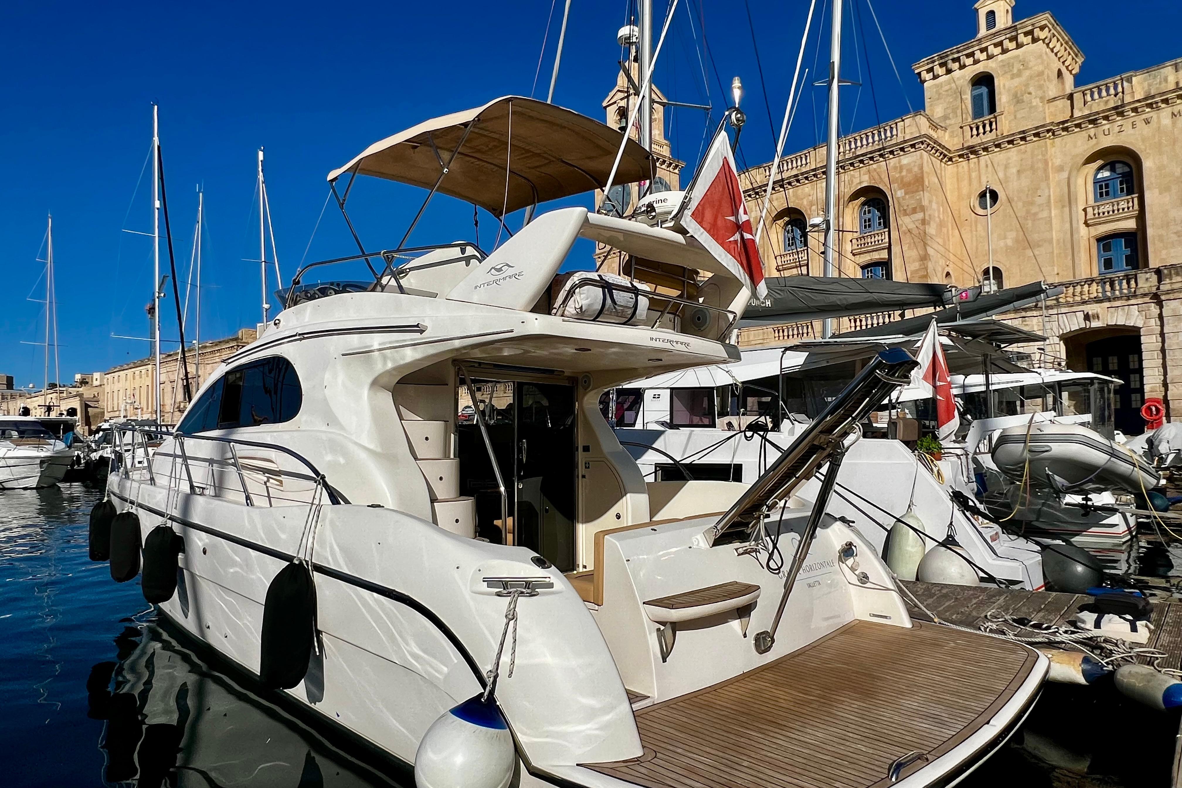 Luxury 2004 Intermare 37 Fly yacht docked in a scenic marina setting.