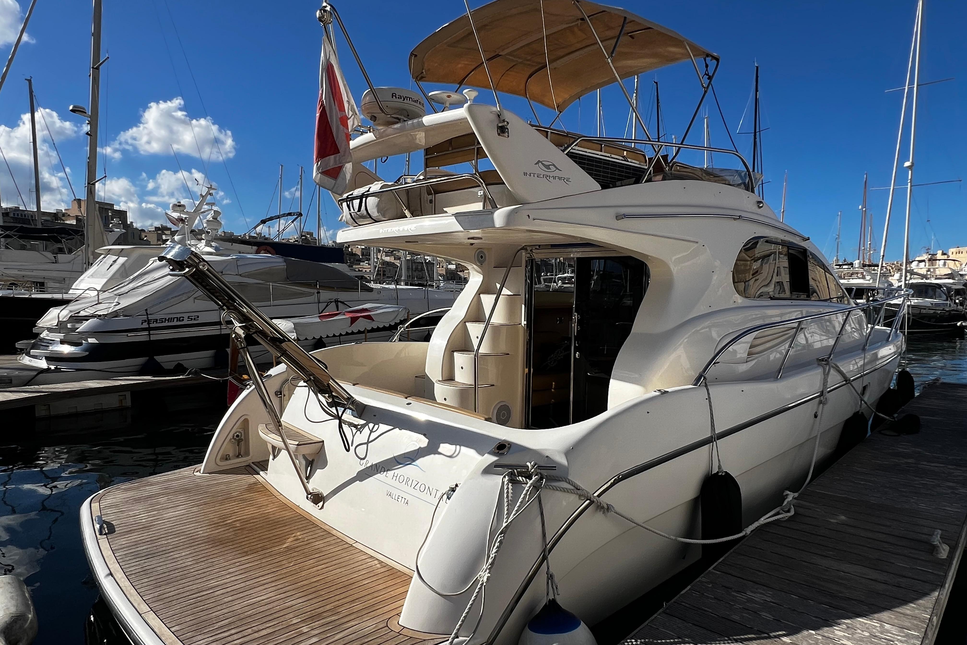 2004 Intermare 37 Fly yacht docked at marina under clear blue sky.
