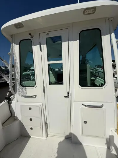  Yacht Photos Pics 2016 Boston Whaler 285 Conquest boat cabin entrance with windows and storage compartments.