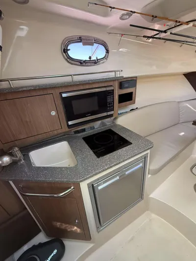  Yacht Photos Pics 2016 Boston Whaler 285 Conquest interior with kitchenette, featuring sink, stove, and microwave.