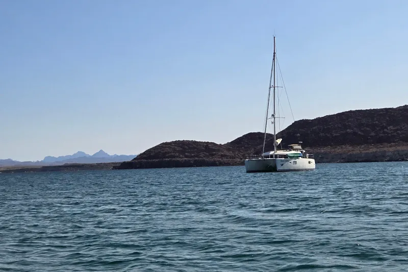 Arias Song Yacht Photos Pics Sailing catamaran Lagoon 400 S2, 2016, anchored near rocky coastline.